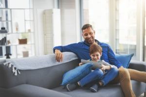 Shot of a cheerful little boy browsing on a digital tablet while lying on his father's lap at home during the day Lenovo Tab P11 Pro und Tab M10 HD Gen 2